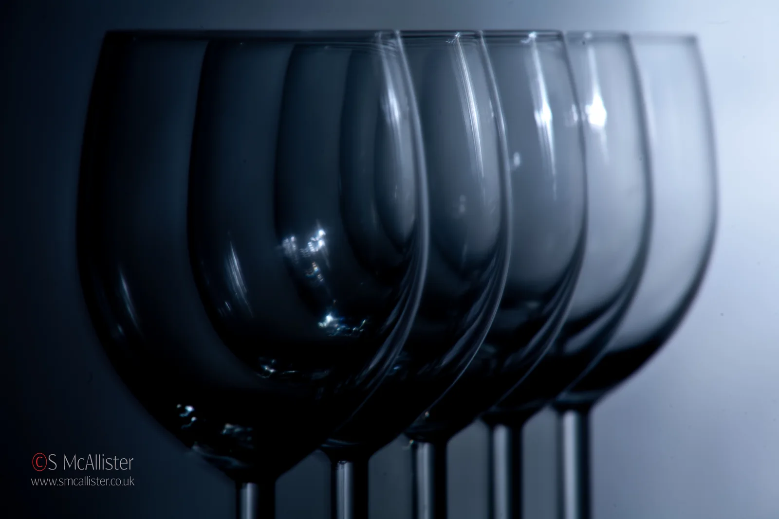 A single blue glass remains sharp as repeated forms recede into haze.