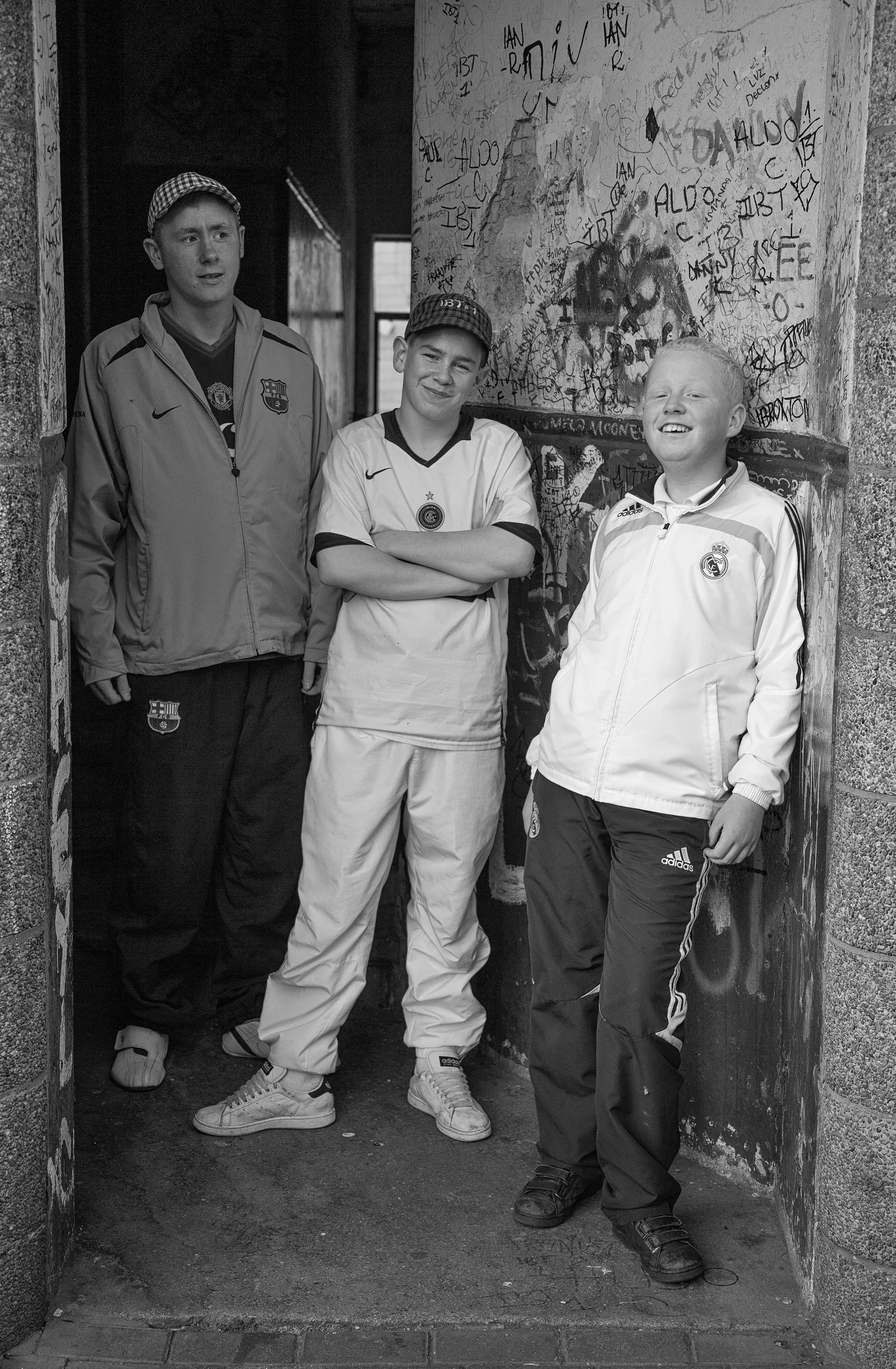 Three young people stand together in a marked doorway.