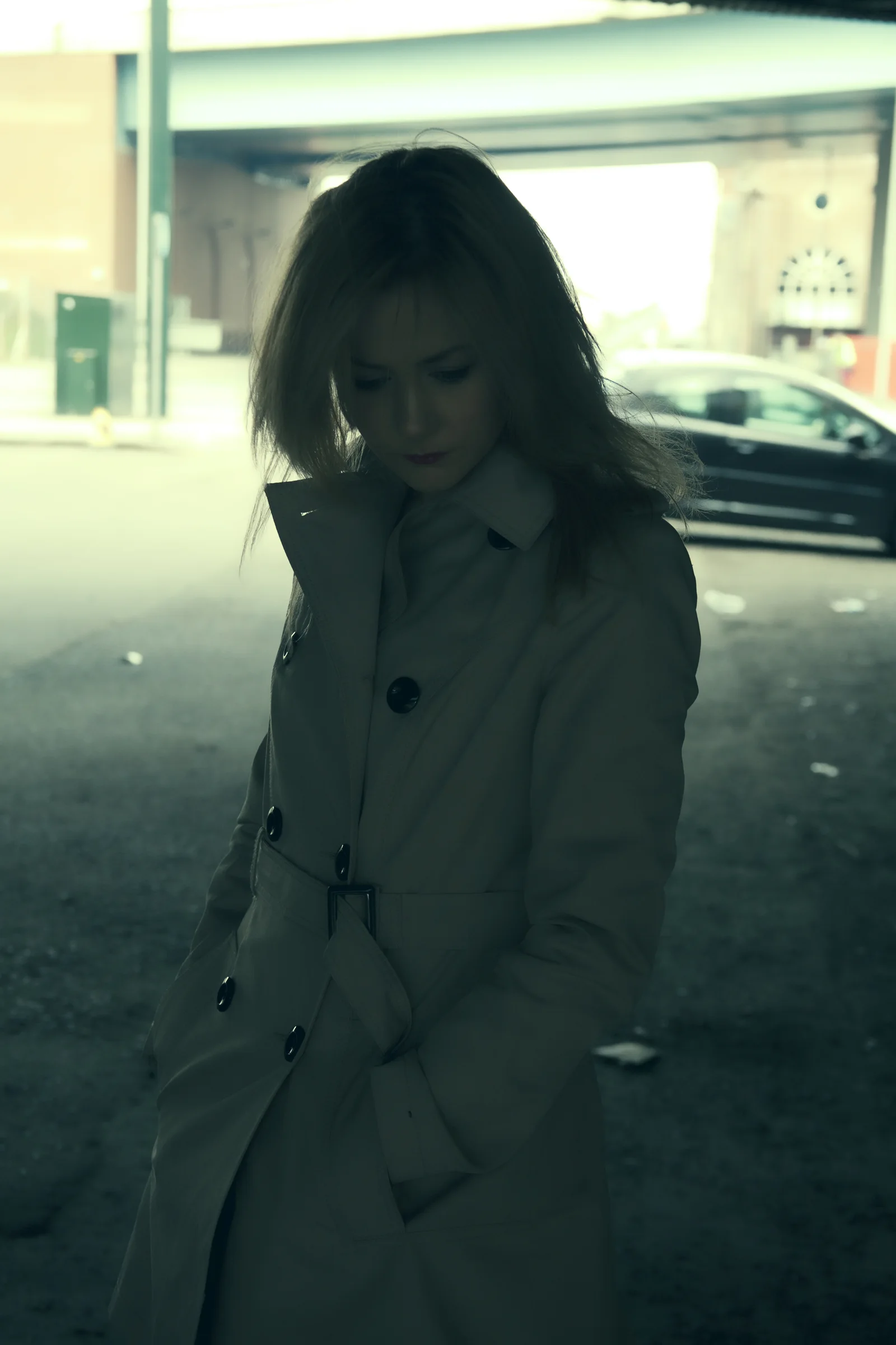 A solitary woman walks through a dim urban setting.