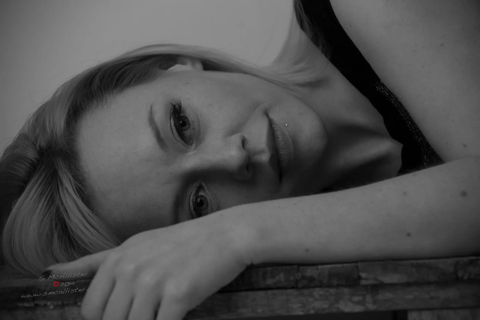 A reclining woman looks toward the camera in a close monochrome portrait.