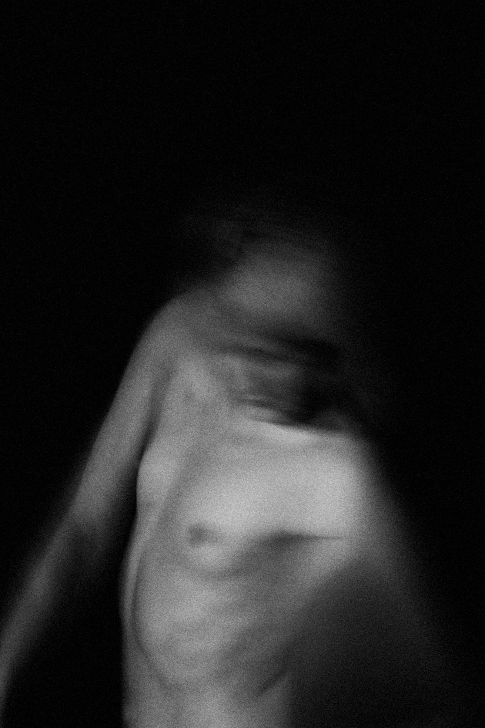 A blurred woman bends forward, her face and body dissolving into a black background.