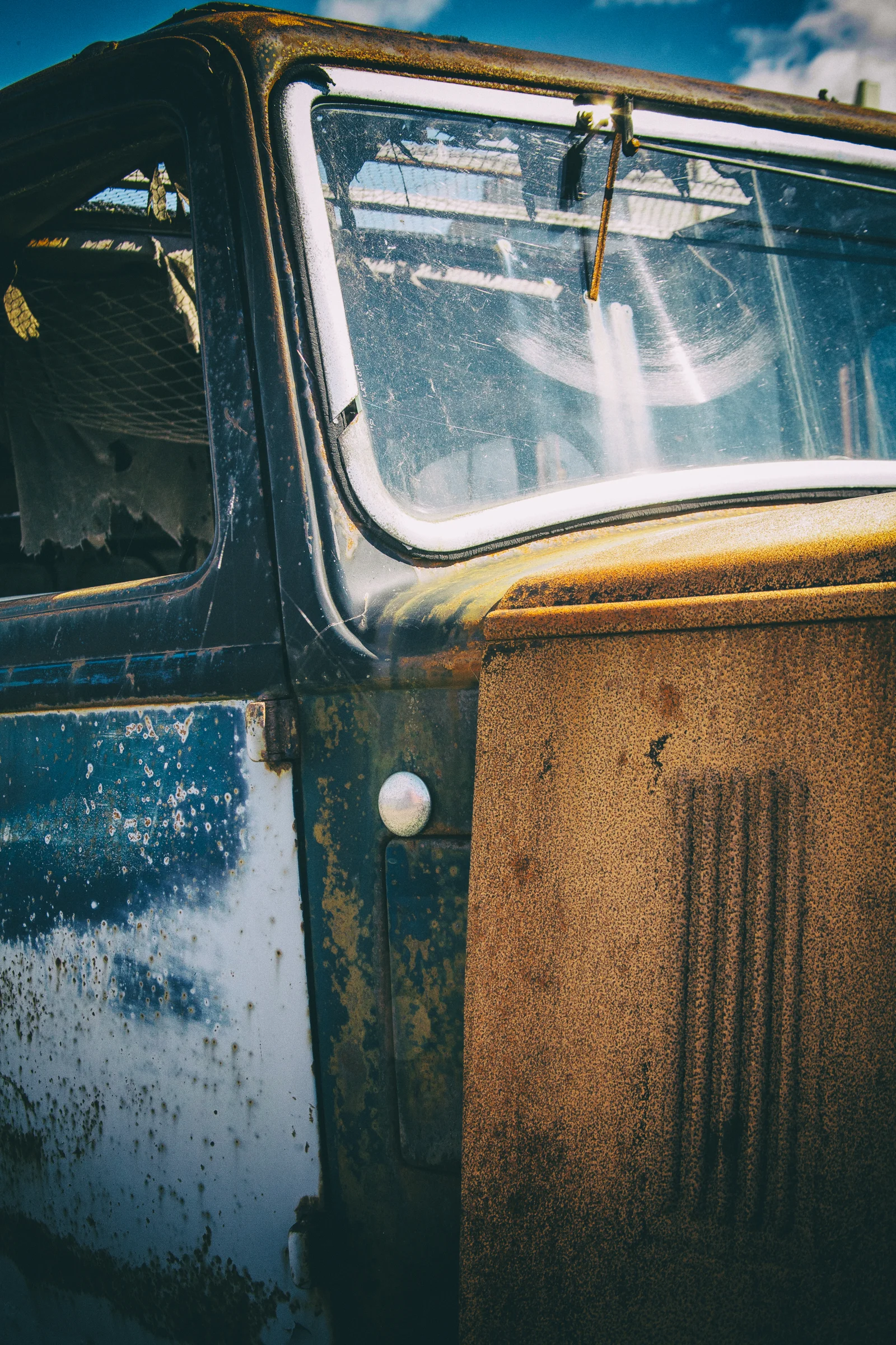Rich blue paint and orange rust cover a weathered industrial surface.